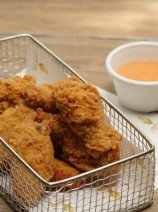 Delicious chicken wings served in a metal tray and accompanied by a miscellaneous orange dip