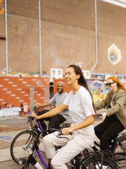 Three people cycling through an eclectic street in Amsterdam