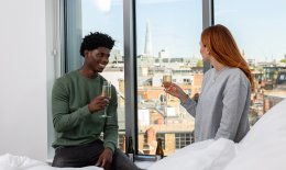 Man and woman holding a glass of champagne looking out of hotel window
