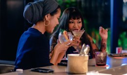 Two women drinking cocktails at bar in Singapore