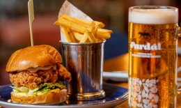 Fried Chicken burger with pint of beer on table