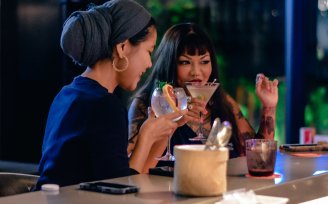 Two women drinking cocktails at bar in Singapore
