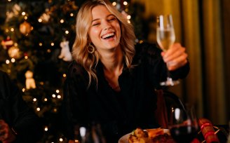 Woman with champagne flute, in front of Christmas tree