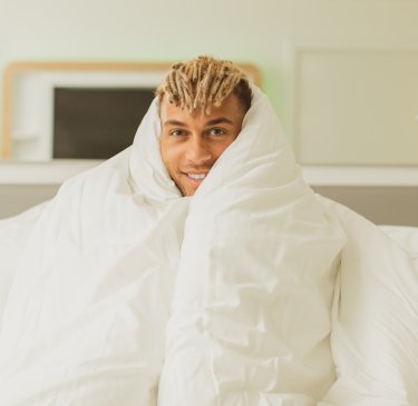 Person in bed with duvet wrapped around them