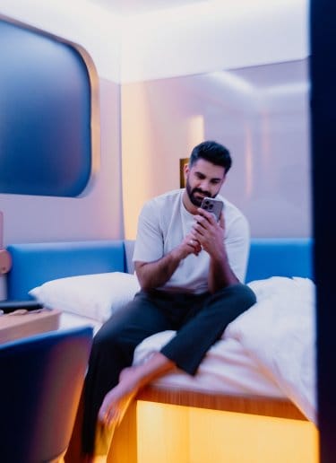 A man relaxes with his phone in his modern airport hotel room