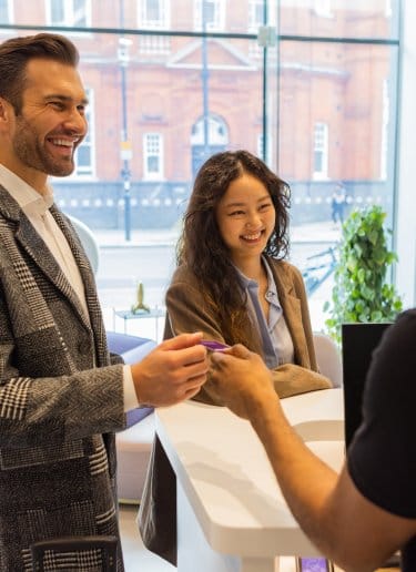 A smartly dressed couple check in to a hotel
