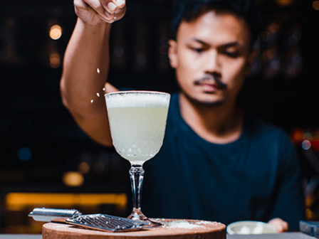 A man with a moustache adds a sprinkle of seasoning to a cocktail 