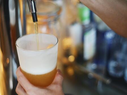 A person pours a draft beer from a hotel bar