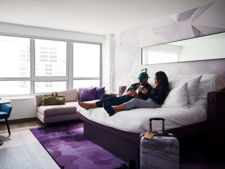 Two people on YOTEL bed looking at their phones