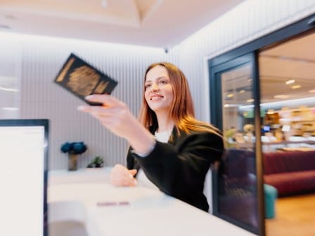 Woman holding up a British Passport at a airport hotel lobby