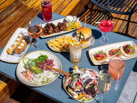 A large platter of food and drinks spread out on a blue table outside