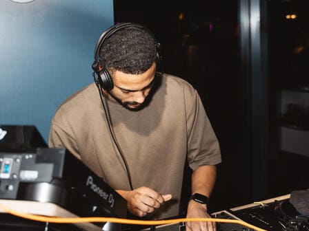 A DJ with black hair works his craft on the turntable