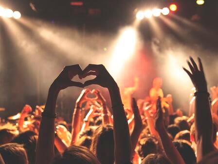 A lively crowd dance in a vibrant room with spotlights and mist