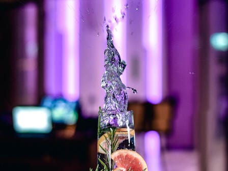 A high ball drink mid-splash with deep purple colours in the background