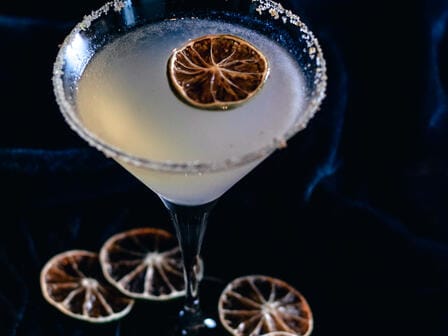 A minimally designed margarita surrounded by fresh fruit for flavour