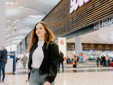 Woman walking through an airport with a large airport hotel in the background