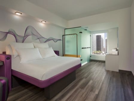 A large hotel room with smartbed, bathroom, and a flatscreen TV