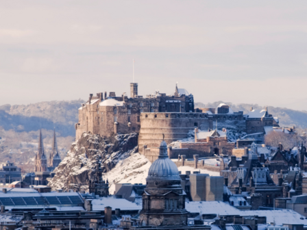 Edinburgh Castle in the snow with Arthur's Seat mountain behind 