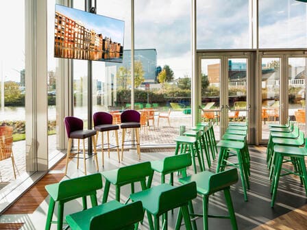 A bright meeting room with chairs laid out towards a TV screen