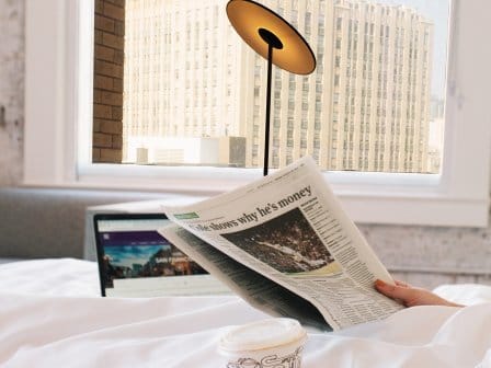Woman in bed drinking coffee with views of San Francisco out the window