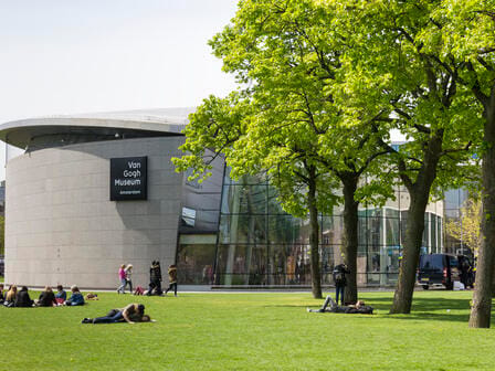 People lying on the grass outside a modern museum building