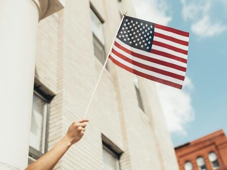 A hand waving the American flag on a sunny day