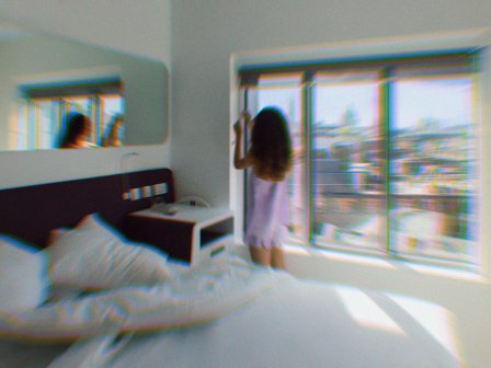Girl in pyjamas in a hotel room looking out to a view of cetral London