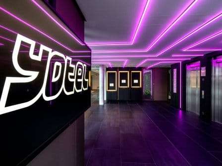 A YOTEL reception, with neon purple lights and self-service check in kiosks