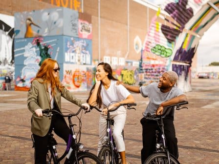 Three people cycling through an eclectic street in Amsterdam