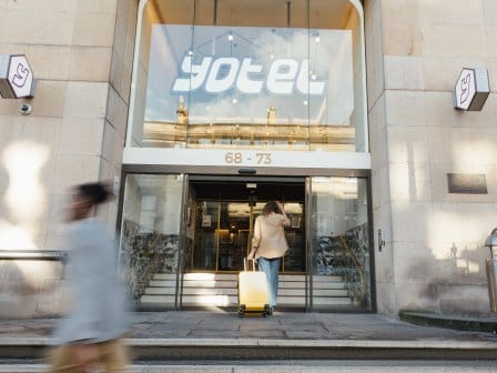 A woman wheels her suitcase into a modern hotel lobby