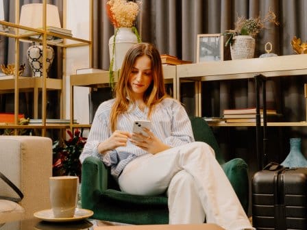 A woman relaxes in a hotel lounge as she plays on her phone 