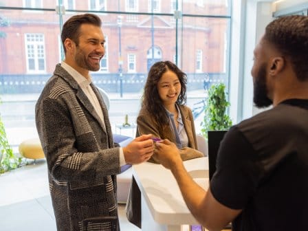 A smartly dressed couple check in to a hotel