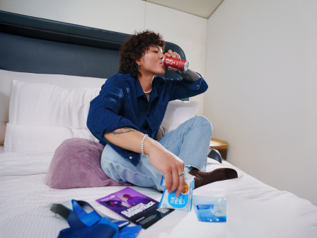 A man drinks an energy drink in bed