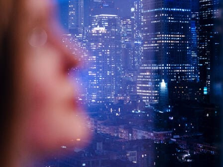 A girl looks out her hotel window at the new york city skyline