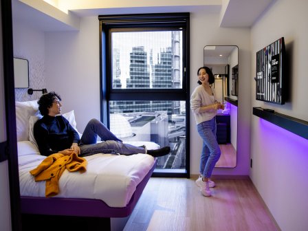 A man and a woman relax in their hotel room with views of Tokyo outside