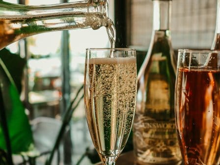 A bottle of prosecco being poured right up to the top of the glass