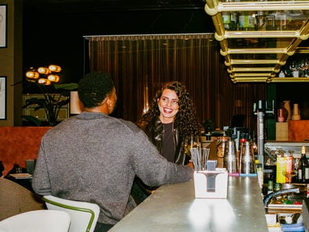 A man and a woman laugh over drinks at a hotel bar