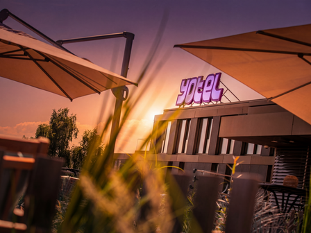 YOTEL property with purple logo and umbrellas during sunset
