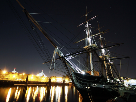 Tall ship during night time and city lights in the distance