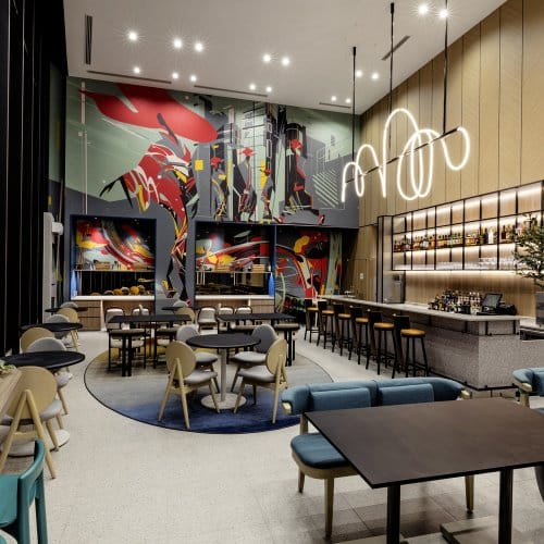 An arty open area of a bar and restaurant with wood panelled walls, sofa seating and bar stools