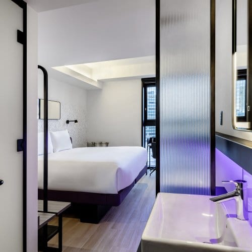 A large Queen Sized Room at YOTEL Tokyo with bright windows and a compact bathroom