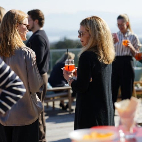 A group of people holding cocktails on a hotel rooftop