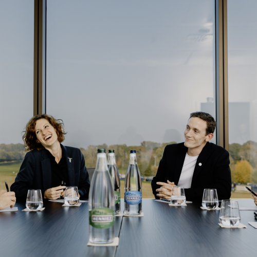 Four people sitting round a boardroom table, laughing 