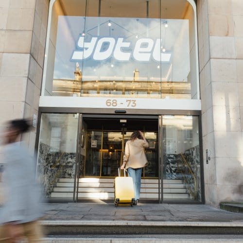 A woman wheels her suitcase into a modern hotel lobby