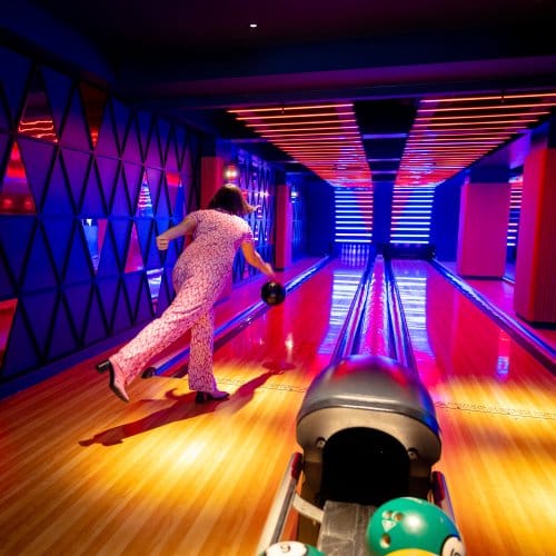 A lady throws a bowling ball down the alley