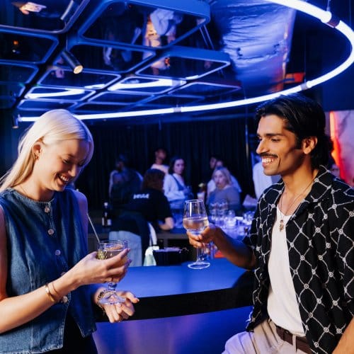 A girl and a man chat at a vibrant circular bar