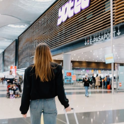 A woman walks towards the front of a large airport hotel. The lettering reads YOTEL