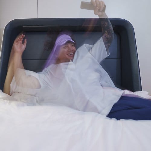 A cheerful man jumps into his hotel bed