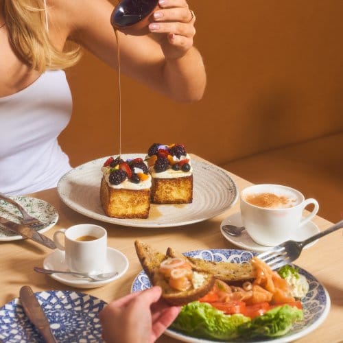 A girl pour syrup on her cake during a buffet breakfast meal