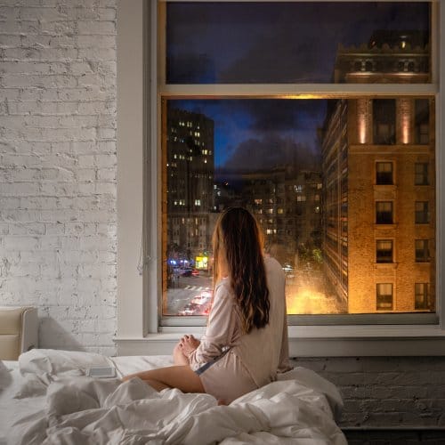A girl relaxes in her hotel bed and admires the view of San Francisco